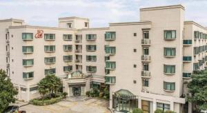 a large white building with green shuttered windows at Jinjiang Inn Select Yangzhou Shouxi Lake Siwangting Road in Yangzhou