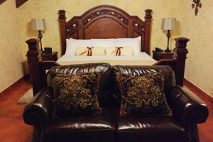 a bedroom with a bed with a leather couch at Hotel Genessis in Antigua Guatemala