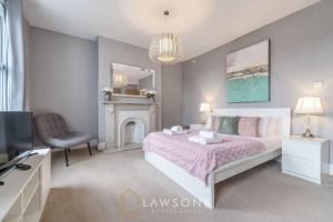 ein Schlafzimmer mit einem Bett und einem Stuhl und einem Fernseher in der Unterkunft Luxury 5BR Villa I Central & Free Parking in Windsor