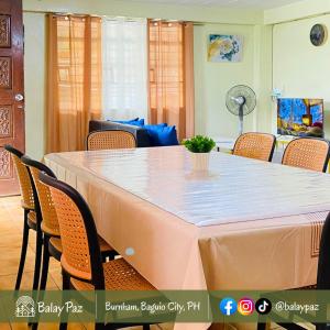 a dining room table with chairs and a white table cloth at Spacious 2BR Family Home - Narra Unit by Balay Paz in Baguio