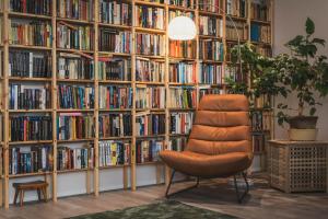 an orange chair in front of a large book shelf at Guesthouse & Caravan Lehtiniemi - Posio in Posio