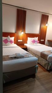 een hotelkamer met 2 bedden en roze kussens bij CleanWave Resort Chumphon คลีนเวฟ รีสอร์ท in Thung Wua Laen Beach