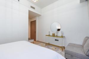 a bedroom with a bed and a chair and a mirror at Westminster ACT1 ACT2 in Dubai