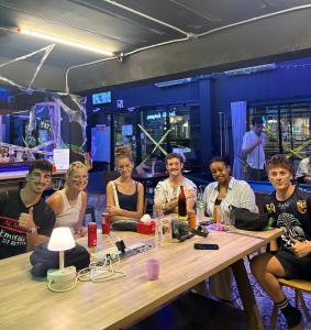 eine Gruppe von Menschen, die um einen Tisch herum sitzen in der Unterkunft Here We Go Bangkok in Bangkok