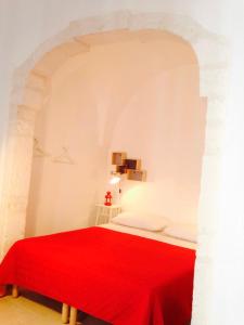 a bedroom with a red bed with a red blanket at L'alcova di Garibaldi in Ostuni