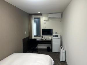 a bedroom with a bed and a desk with a microwave at 未来ホテル MiraiHotel in Isesaki