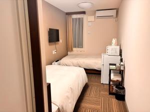 a hotel room with two beds and a television at 未来ホテル MiraiHotel in Isesaki