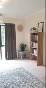 a room with a book shelf and a clock on the wall at Peaceful Rural Cottage in Kopuaranga