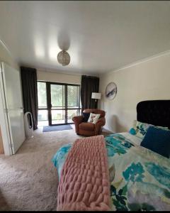 a bedroom with a bed and a chair in it at Peaceful Rural Cottage in Kopuaranga +5 photos