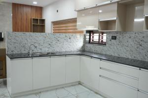 a kitchen with white cabinets and a sink at Oceanus Retreat in Mayyanād