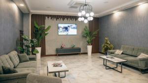 a living room with couches and tables and plants at Alis Business Hotel baku in Baku
