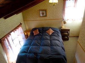 a bedroom with a blue comforter on a bed at Posada del Buscador in El Bolsón