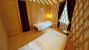 a small room with two beds and a window at Gîte Les yourtes de Saint Mathieu N°1 in Saint-Mathieu