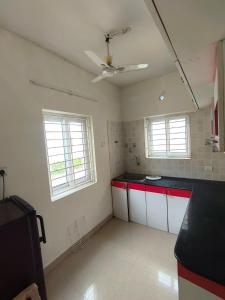 a kitchen with red and white cabinets and two windows at SK INN stays in Mahabalipuram