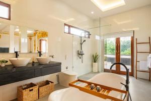 ein Badezimmer mit zwei Waschbecken und einem großen Spiegel in der Unterkunft Private Luxe 5BR Swarna Mandapa By Orivista in Uluwatu + 19 Fotos