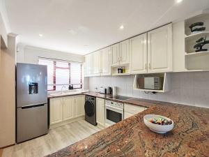 een keuken met witte kasten en een fruitschaal op een aanrecht bij Ocean Blue Stay in St James