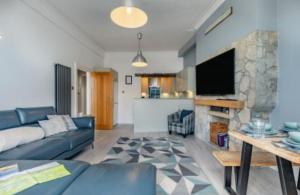 een woonkamer met een blauwe bank en een stenen open haard bij Ocean view in Swanage