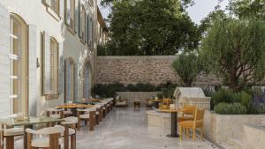 un ristorante con tavoli e sedie e un cortile di Hôtel de La Fontaine a Lourmarin