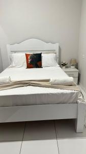 a white bedroom with a large white bed with an orange pillow at T2 Vacation in Mindelo in Mindelo
