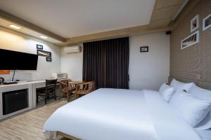 a hotel room with a white bed and a desk at Jeonju Nabi in Jeonju