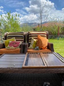 a wicker couch with pillows and a table at Arpi GuestHouse Dilijan in Dilijan