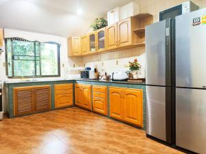 eine Küche mit Holzschränken und einem Edelstahlkühlschrank in der Unterkunft Yellow hourse Luxury Pool Villa in Chiang Mai