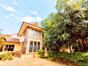 ein gelbes Haus mit einem Baum davor in der Unterkunft Yellow hourse Luxury Pool Villa in Chiang Mai