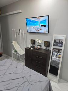 a bedroom with a dresser and a tv on the wall at El Rincón in Tunapuna