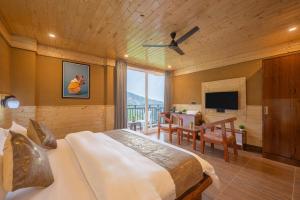 a bedroom with a bed and a desk and a television at The Charvi Retreat Kufri I Vacations I Conference I MICE I Family Events I Open Air Terrace I Sky Bonfire I Wooden Rooms With Pvt Balconies I Kufri by Exotic Stays in Kūfrī +63 photos
