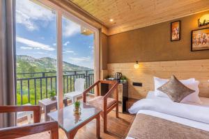 a bedroom with a balcony with a bed and a table at The Charvi Retreat Kufri I Vacations I Conference I MICE I Family Events I Open Air Terrace I Sky Bonfire I Wooden Rooms With Pvt Balconies I Kufri by Exotic Stays in Kūfrī