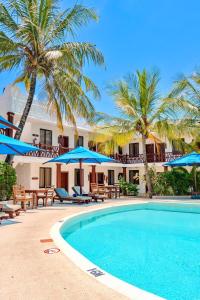 a resort with a swimming pool with palm trees and umbrellas at PrideInn Hotel Nyali in Mombasa