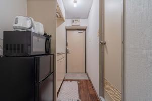a kitchen with a refrigerator and a door to a hallway at 3 minutes walk from Minami Fukuoka Station, free Wi-Fi in Fukuoka