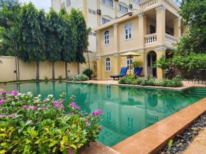 a swimming pool in front of a house with flowers at La Villa in Battambang
