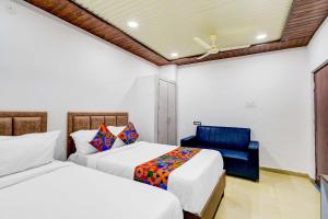ハイデラバードにあるFabHotel Devara Grandのベッドルーム1室(ベッド2台、青い椅子付)