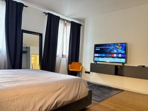 a bedroom with a bed and a flat screen tv at Elegante appartamento nel cuore di Bassano in Bassano del Grappa