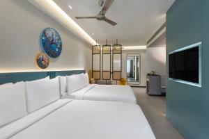 um quarto com uma grande cama branca e uma televisão de ecrã plano em ZIBE Luxe Hyderabad by GRT Hotels em Hyderabad mais 16 fotografias