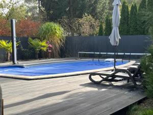 a swimming pool with an umbrella and a chair and an umbrella at Harmony Spa Matyldów in Matyldów