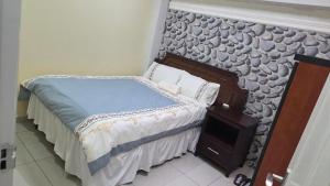 a small bedroom with a bed with a wall at Ntale Guest House in Benoni