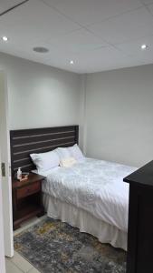 a bedroom with a bed and a wooden night stand at Ntale Guest House in Benoni