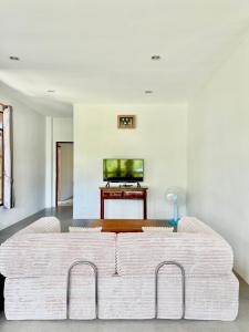 een woonkamer met een witte bank en een televisie bij Baan Suan Poolsap - Haad Rin Beach in Haad Rin
