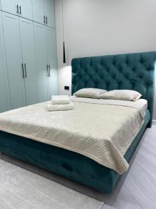 a bedroom with a large bed with a blue headboard at Elexus Estate in Astana