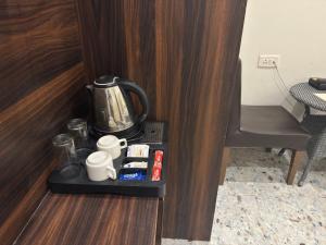 a coffee maker and cups on a tray in a room at Hotel Vrinda Sarovar in Mathura