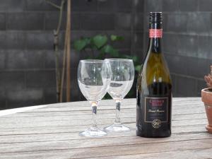 a bottle of wine and two wine glasses on a table at By The Sea On Sackville - beachside in Fitzroy in New Plymouth