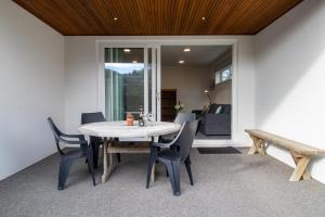 a dining room with a table and chairs and a bench at By The Sea On Sackville - beachside in Fitzroy in New Plymouth