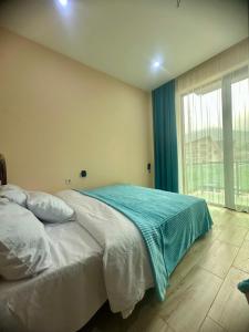 a bedroom with a bed and a large window at Snow Forest ԲԱԿՈՒՐԻԱՆԻ-ბაკურიანი-BAKURIANI in Bakuriani