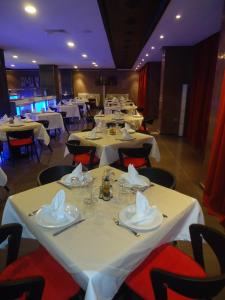 une salle à manger avec des tables blanches et des chaises rouges dans l'établissement Hotel Emilio Moretti, à Laâyoune