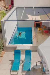 a person swimming in a pool with two blue chairs at Villa Marisari in Otok Lastovo