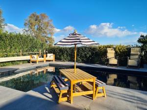 a table and chairs with an umbrella next to a pool at Portion of a villa with a private pool in Ansedónia