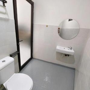 a bathroom with a toilet and a sink and a mirror at The W Residence in Jakarta