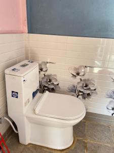 a white toilet in a bathroom with flowers on the wall at Karfok Khalanga community homestay in Ilām